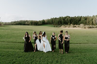 bride and bridesmaids walking together through field