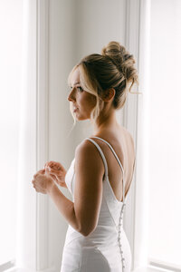 Engagement photography session with the bride-to-be wearing a veil and a white suit and the soon to be groom in a white shirt and suspenders as they walk towards Lake George, New York.