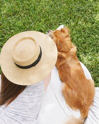 girl laying out on a blanket on the grass with her dog