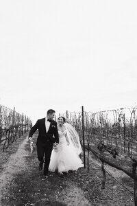bride and groom walking through vineyard 