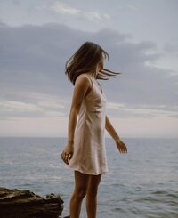 Woman walking along the shoreline, representing individual therapy and coaching for women seeking clarity, calm, and connection through feminist, values-based counseling.