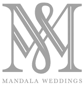 Logo of Mandala Weddings featuring a stylized, interwoven letter M in a classic serif font. The words Mandala Weddings are written below in smaller text. The overall design is in a subtle gray color.