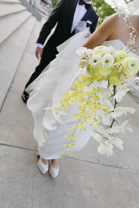 Close-up of bride holding bright yellow bouquet and modern gown, shot in editorial fine-art wedding style.