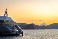 Private yacht anchored at sea under a golden sunset sky.