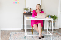 Becca sitting in her sunlit office at her desk