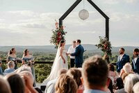 Bride and groom posing on a wooden platform overlooking the hills near Nashville, TN—moody skies and sweeping views frame this cinematic wedding portrait.
