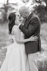A female bride and male groom embrace one another outside. 