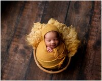 Brooklyn newborn photographer with baby wrapped in mustard wrap laying on fur