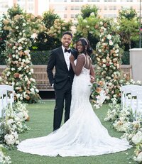 Couple portrait in front of their fall colored ceremony backdrop on a n Atlanta rooftop venue the Epicurean