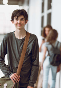 Teenager walking with brown bag and gray shirt