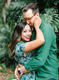 engagement photography at botanical garden in pasadena bride holding groom's face and smiling at the camera