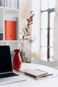 red vase next to computer on a white table