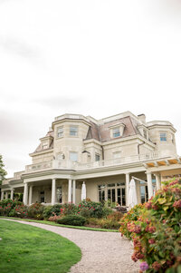 A stunning view of The Chanler at Cliff Walk’s historic exterior, surrounded by manicured gardens. This iconic Newport mansion offers ocean views, timeless charm, and refined elegance for a dream wedding or luxury stay.