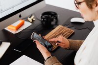 woman sitting at desk holding cell phone