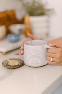 Merlyn Asencio holding a cup of tea on the counter, embodying a soothing and nurturing environment central to her trauma therapy practice in Miami, Florida
