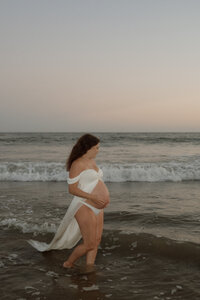 mom with daughter walking on coastline during family photos