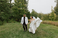 Bride and groom running to the camera hand in hand smiling at each other.