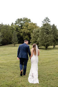 bride and groom walking through field