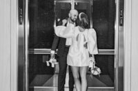 bride and groom share a kiss as he holds her high heels after charlotte wedding