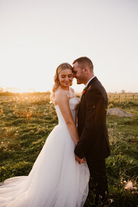 Natasha and shaun holding hands as the sunsets while aimee kelly photographs them in taranaki during their wedding photoshoot