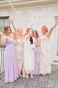 Sophie pops a bottle of champagne while her bridesmaids cheer on the terrace.