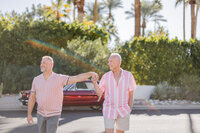 A sun-drenched celebration of LGBTQ+ love in Palm Springs. This vibrant moment of connection, classic style, and effortless romance unfolds against a vintage red Mustang and lush greenery, embodying timeless joy and authenticity.
