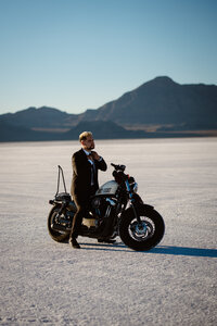 Groom poses on motorcycle after his elopement on the Bonneville Salt Flats in Utah.
