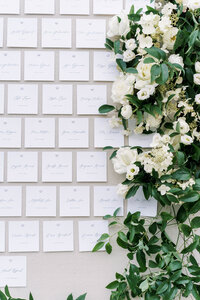 linen covered escort card display with large greenery and floral designs at the monastery event center by cincinnati wedding florist roots floral design