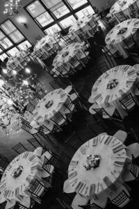 Elegant black and white overhead view of round dining tables with white linens and floral centerpieces in a banquet hall at River Run Lodge in Redmond, Oregon.