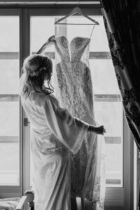 Bride holding her dress and smiling by window in the Dolomites
