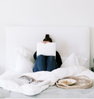 Woman on laptop in messy bed