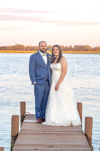 Wedding couples standing on a dock during their wedding day.