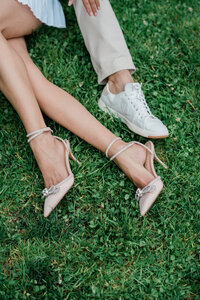 The shoes of a man and woman laying in a grassy field in a Tribeca park