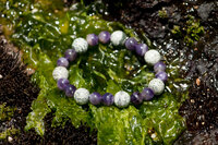 A Moss Agate and Amethyst Bracelet laying on Moss.
