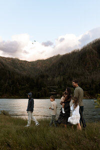 Family of six walking along a river with mountains in the background