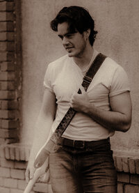 A musician poses in the rain with his electric guitar.