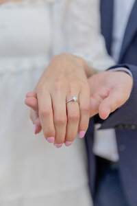 A North Carolina bride shows up her wedding ring in a close up shot. Her groom holds her hand underneath. 