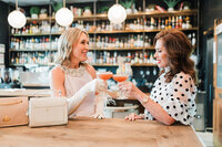 Two wedding planners toast with cocktails at a stylish bar, capturing the friendly and vibrant approach of Socially Significant Events to event planning.