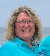 Client Julie smiling at the camera wearing teal polo shirt