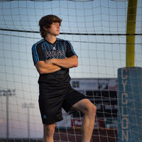 high school senior boy posing in front a  soccer net