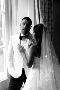 A bride snuggles on her groom inside in black and white