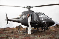 A bride pauses  on a step of a helicopter for a photo after landing high above a glacier in Alaska.