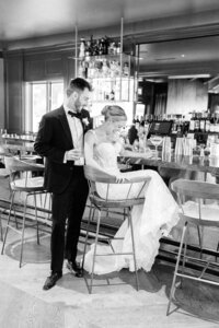 bride and groom at a bar setting while drinking cocktails and laughing
