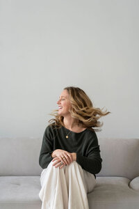 Kaitlyn David smiling and looking to the side while sitting on a couch with a blanket