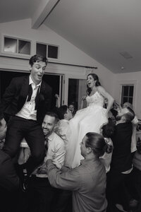 A joyful wedding celebration with guests lifting the bride and groom, showcasing TM Photo Co.’s expertise in capturing candid, emotional moments with a luxury wedding photography style.