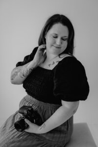 Black and white photograph of photographer Bethany Simms holding a camera and looking down