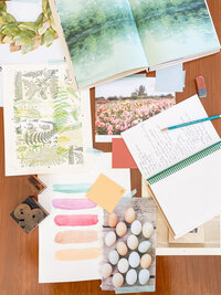 Flatlay of papers, books, a stamp, notebook and pencil