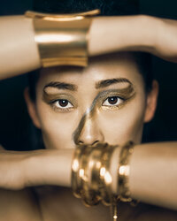 beautiful Asian woman wearing gold bangles and artistic gold makeup