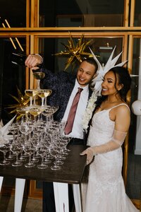 A bride and groom pour a champagne tower at their wedding.