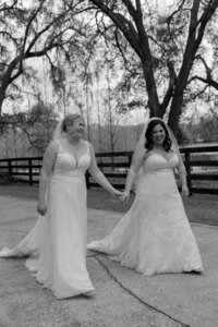Two joyful brides walking hand in hand in lace wedding gowns at Club Lake Plantation in Apopka, Florida — candid LGBTQ+ wedding moment filled with love and laughter.